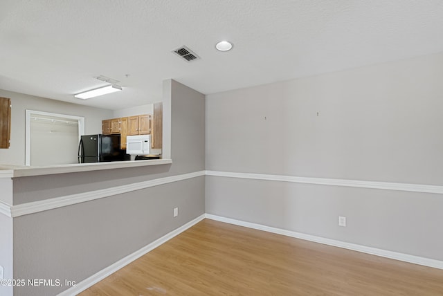 kitchen with black refrigerator, light hardwood / wood-style floors, and a textured ceiling