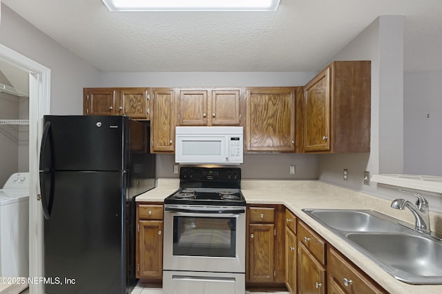 kitchen with washer / dryer, sink, black fridge, a textured ceiling, and stainless steel electric range