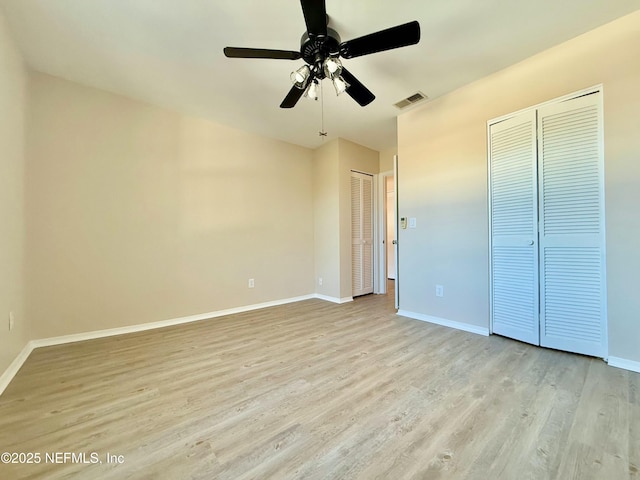 unfurnished bedroom with two closets, ceiling fan, and light hardwood / wood-style flooring