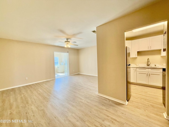 unfurnished living room featuring ceiling fan, sink, and light wood-type flooring