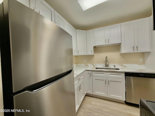 kitchen with light stone counters, stainless steel appliances, sink, and white cabinets