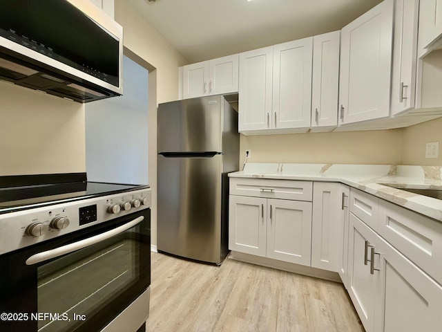 kitchen with sink, appliances with stainless steel finishes, light stone counters, light hardwood / wood-style floors, and white cabinets