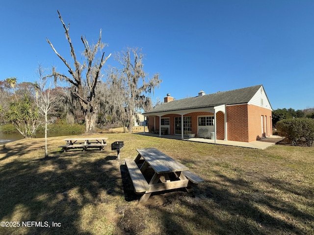 back of property with a yard and a patio area