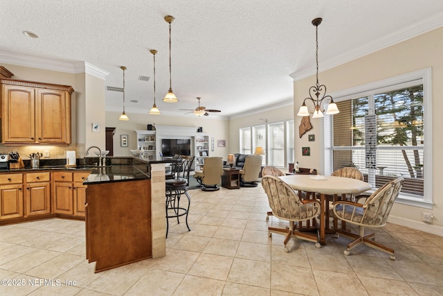 tiled dining space featuring ornamental molding, sink, ceiling fan with notable chandelier, and a textured ceiling