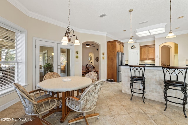 tiled dining space featuring french doors, ceiling fan, ornamental molding, and a textured ceiling