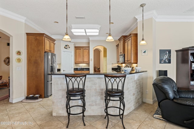 kitchen with a kitchen bar, a textured ceiling, kitchen peninsula, pendant lighting, and stainless steel appliances