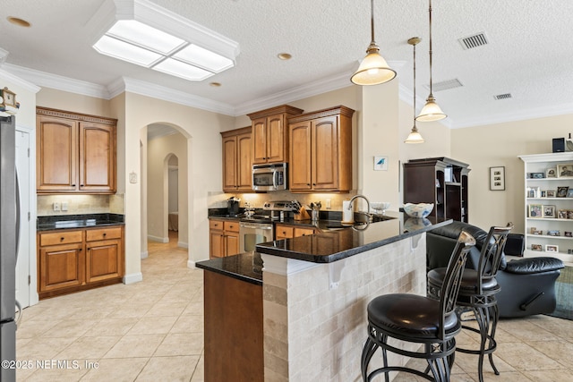 kitchen with pendant lighting, sink, light tile patterned floors, appliances with stainless steel finishes, and ornamental molding