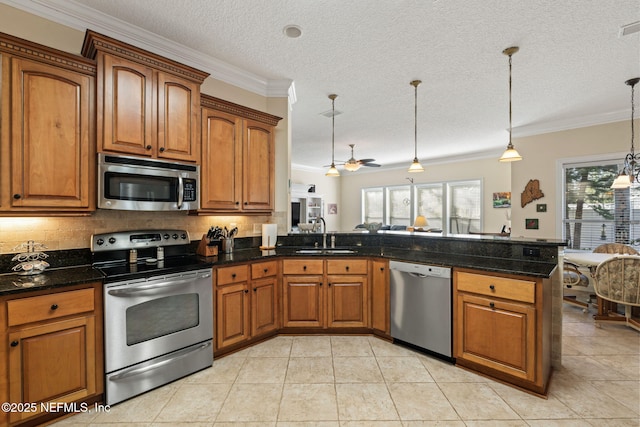 kitchen with decorative light fixtures, sink, ornamental molding, stainless steel appliances, and a textured ceiling