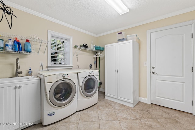 washroom featuring washing machine and clothes dryer, sink, cabinets, a textured ceiling, and light tile patterned floors