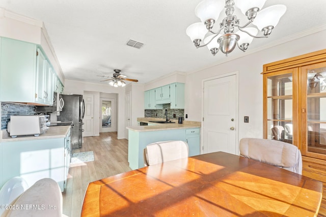 dining space featuring crown molding, sink, ceiling fan with notable chandelier, and light hardwood / wood-style floors