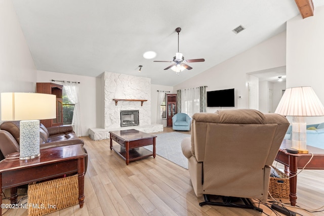 living room with ceiling fan, high vaulted ceiling, a fireplace, and light hardwood / wood-style flooring