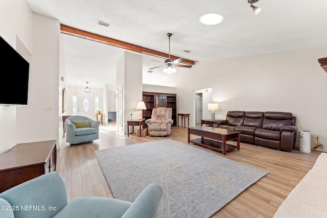 living room with lofted ceiling with beams, ceiling fan, a textured ceiling, and light wood-type flooring