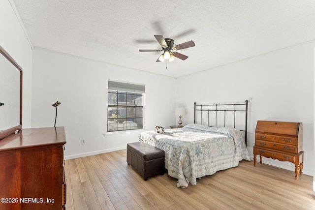 bedroom with ceiling fan, a textured ceiling, and light hardwood / wood-style flooring