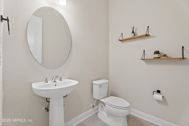 half bathroom with toilet and baseboards