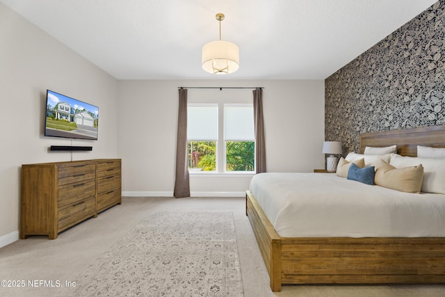 carpeted bedroom featuring an accent wall, baseboards, and wallpapered walls