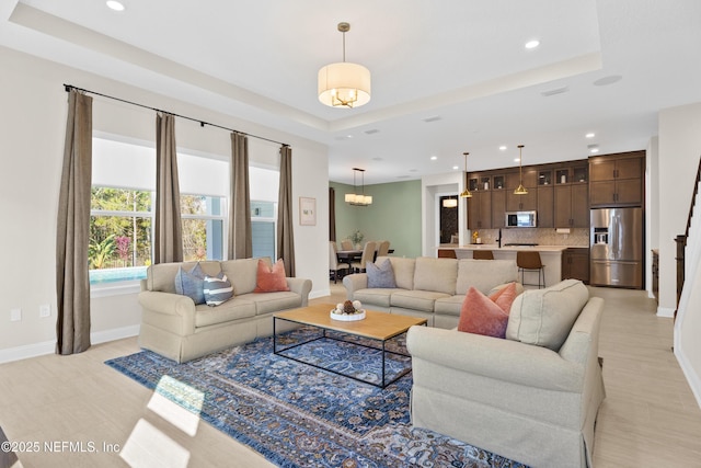 living area with baseboards and a raised ceiling