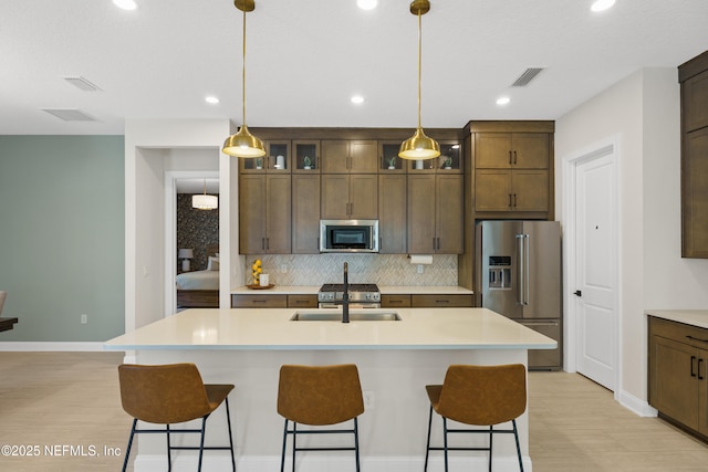 kitchen featuring visible vents, appliances with stainless steel finishes, a kitchen breakfast bar, and backsplash