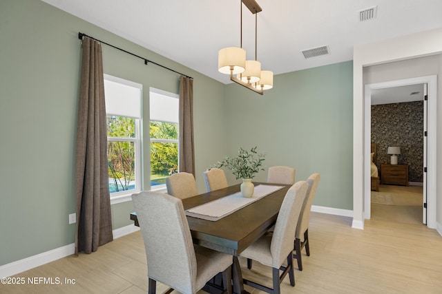 dining space with baseboards, visible vents, and light wood finished floors