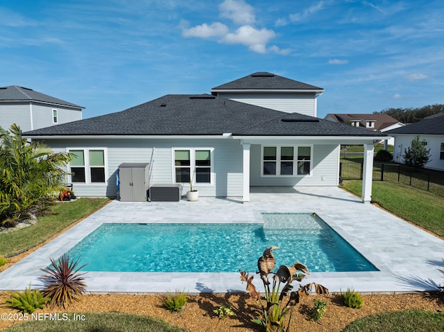 rear view of house with a fenced in pool, a shingled roof, a lawn, a patio area, and fence