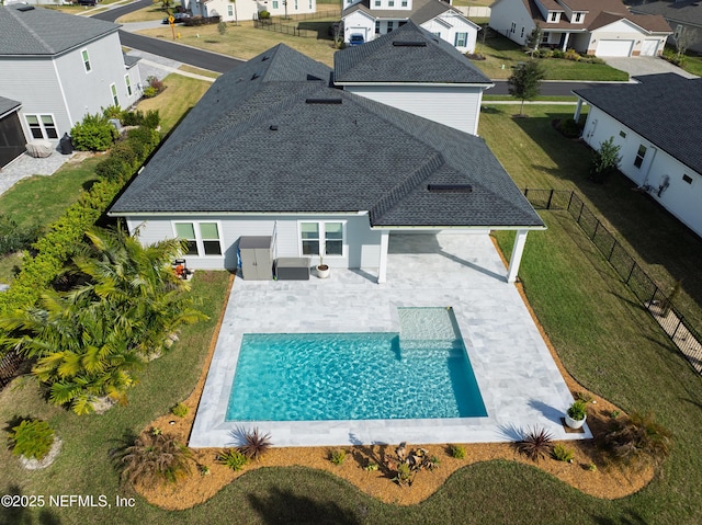 back of property featuring a shingled roof, an outdoor pool, a fenced backyard, a residential view, and a patio area