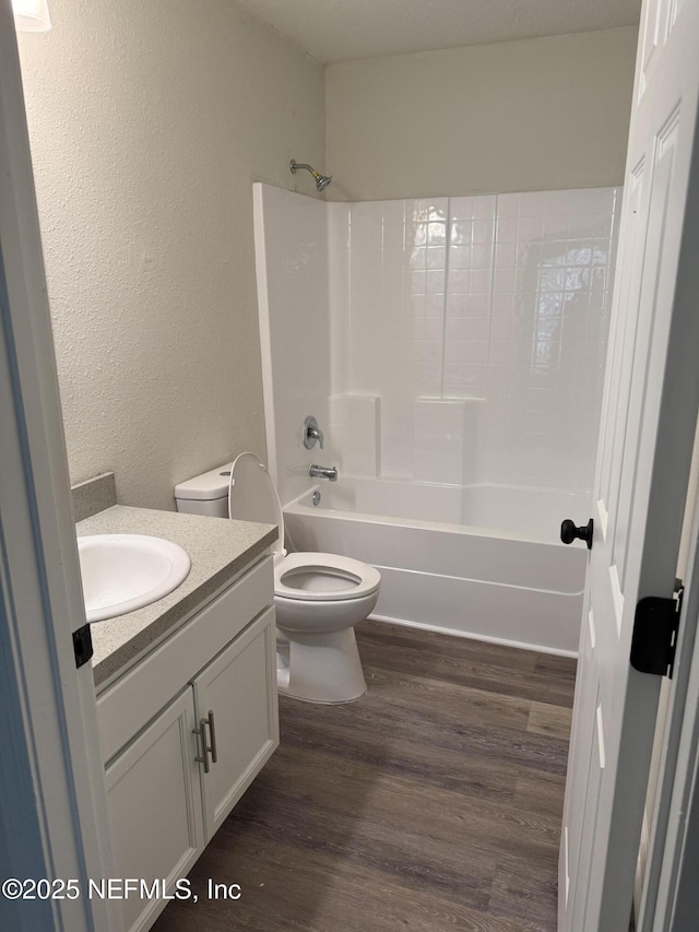 full bathroom featuring vanity, hardwood / wood-style flooring, bathing tub / shower combination, and toilet