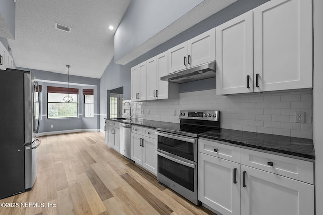 kitchen with lofted ceiling, sink, white cabinetry, and appliances with stainless steel finishes