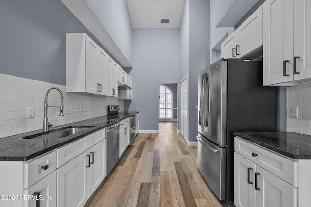 kitchen featuring white cabinetry, appliances with stainless steel finishes, sink, and dark stone countertops