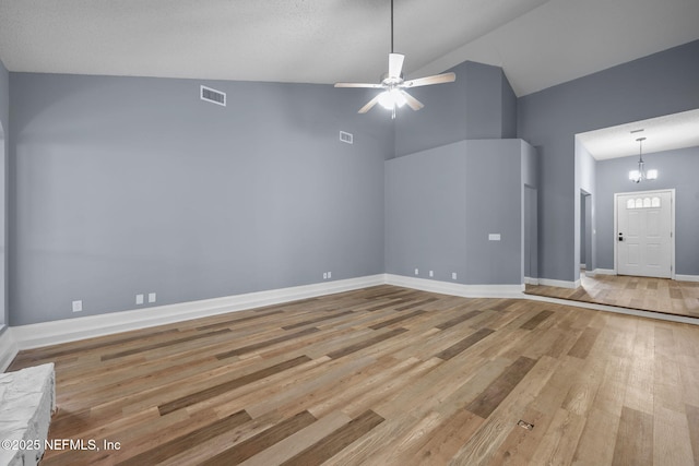 unfurnished living room featuring light wood-type flooring, ceiling fan with notable chandelier, and high vaulted ceiling