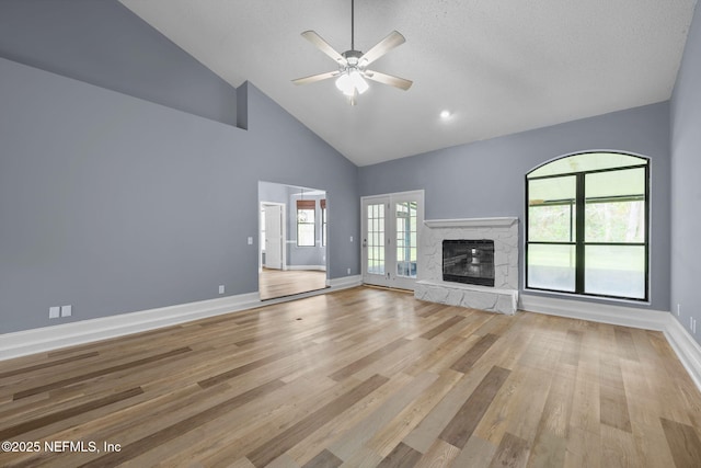 unfurnished living room with a stone fireplace, light hardwood / wood-style floors, and a healthy amount of sunlight