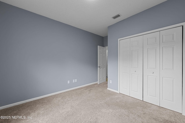 unfurnished bedroom with light colored carpet and a closet