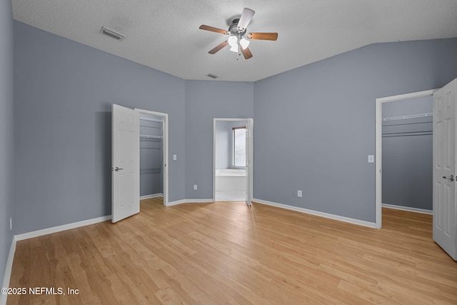 unfurnished bedroom featuring vaulted ceiling, light wood-type flooring, a textured ceiling, and ceiling fan