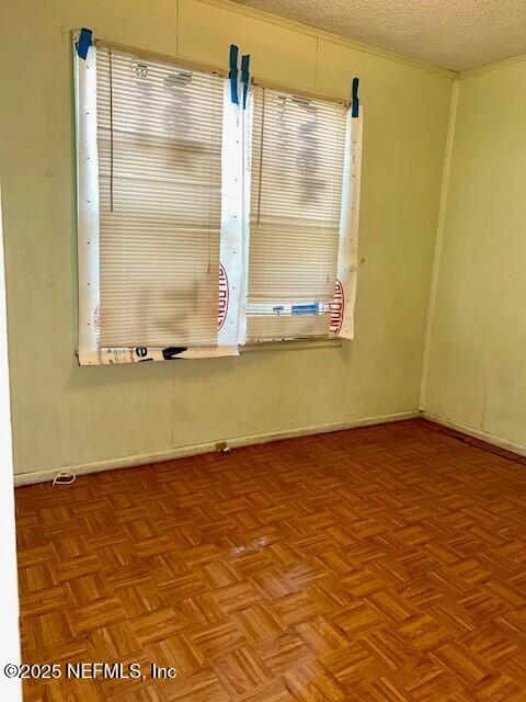 spare room featuring light parquet flooring and a textured ceiling