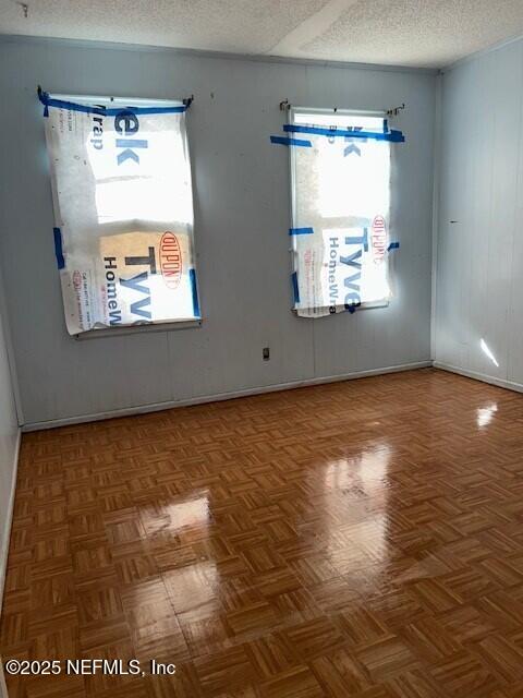 unfurnished room featuring parquet flooring and a textured ceiling