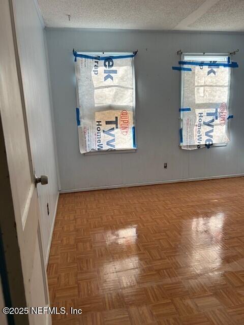 spare room featuring plenty of natural light, a textured ceiling, and parquet flooring