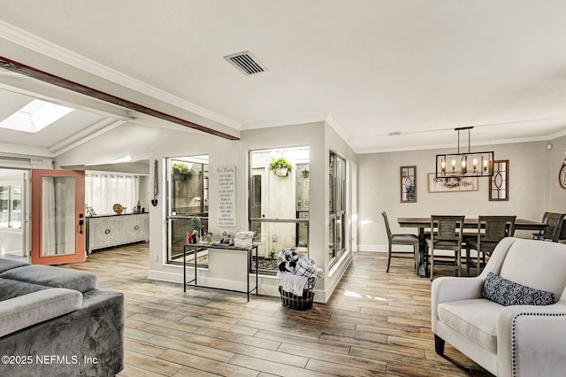 living room with crown molding, lofted ceiling with skylight, light hardwood / wood-style floors, and a notable chandelier