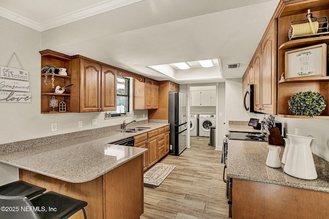 kitchen with light stone counters, kitchen peninsula, sink, and washing machine and dryer