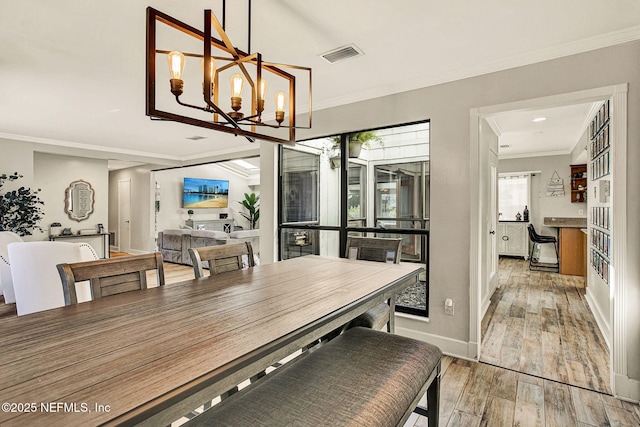 dining space with ornamental molding, wood-type flooring, a notable chandelier, and plenty of natural light