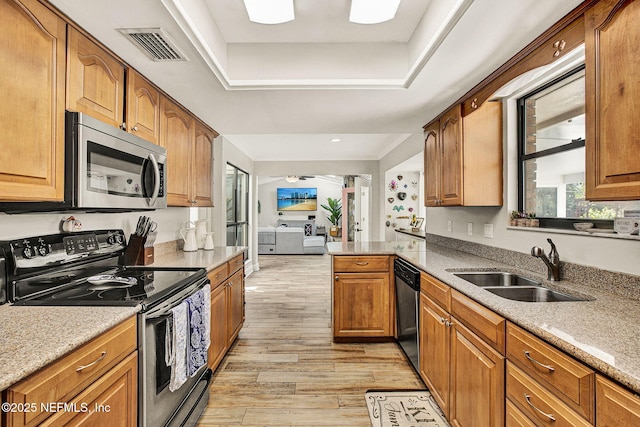 kitchen with sink, light hardwood / wood-style flooring, a raised ceiling, kitchen peninsula, and stainless steel appliances