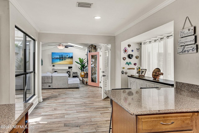 kitchen featuring light stone counters, crown molding, light hardwood / wood-style flooring, and ceiling fan