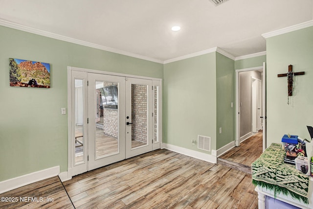 entrance foyer featuring french doors, ornamental molding, and light hardwood / wood-style flooring