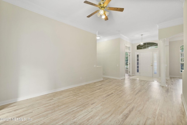 unfurnished room with decorative columns, crown molding, ceiling fan, and light wood-type flooring