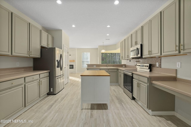 kitchen featuring sink, appliances with stainless steel finishes, butcher block counters, light hardwood / wood-style floors, and decorative light fixtures