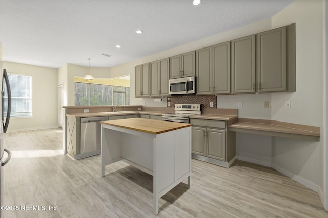 kitchen with appliances with stainless steel finishes, wooden counters, backsplash, hanging light fixtures, and a center island