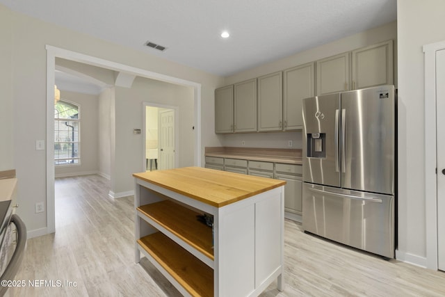 kitchen with butcher block counters, stainless steel fridge with ice dispenser, gray cabinets, and light hardwood / wood-style floors