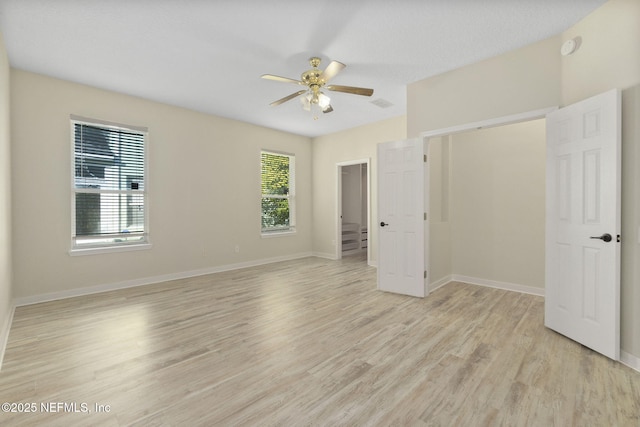 unfurnished bedroom with a walk in closet, light hardwood / wood-style floors, a closet, and ceiling fan