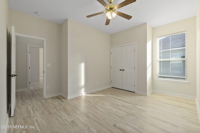 unfurnished bedroom featuring ceiling fan, light hardwood / wood-style floors, and a closet