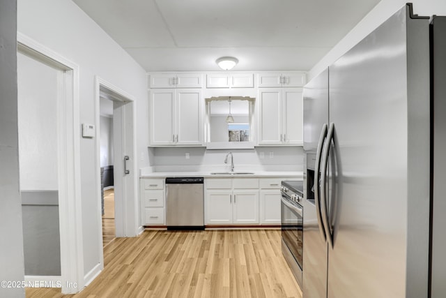 kitchen featuring white cabinetry, sink, light hardwood / wood-style flooring, and appliances with stainless steel finishes