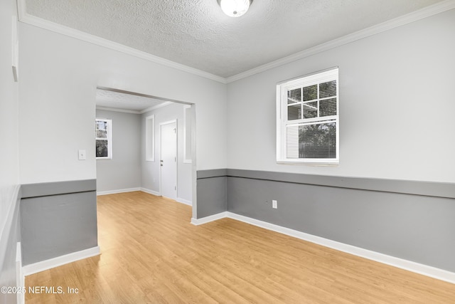 empty room featuring hardwood / wood-style flooring, a wealth of natural light, ornamental molding, and a textured ceiling