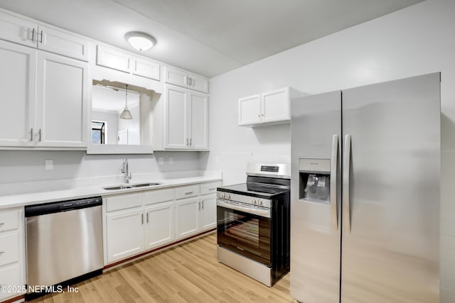 kitchen with sink, appliances with stainless steel finishes, hanging light fixtures, light hardwood / wood-style floors, and white cabinets