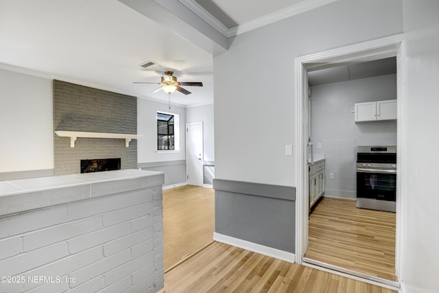 kitchen featuring a fireplace, white cabinetry, ornamental molding, light hardwood / wood-style floors, and electric stove